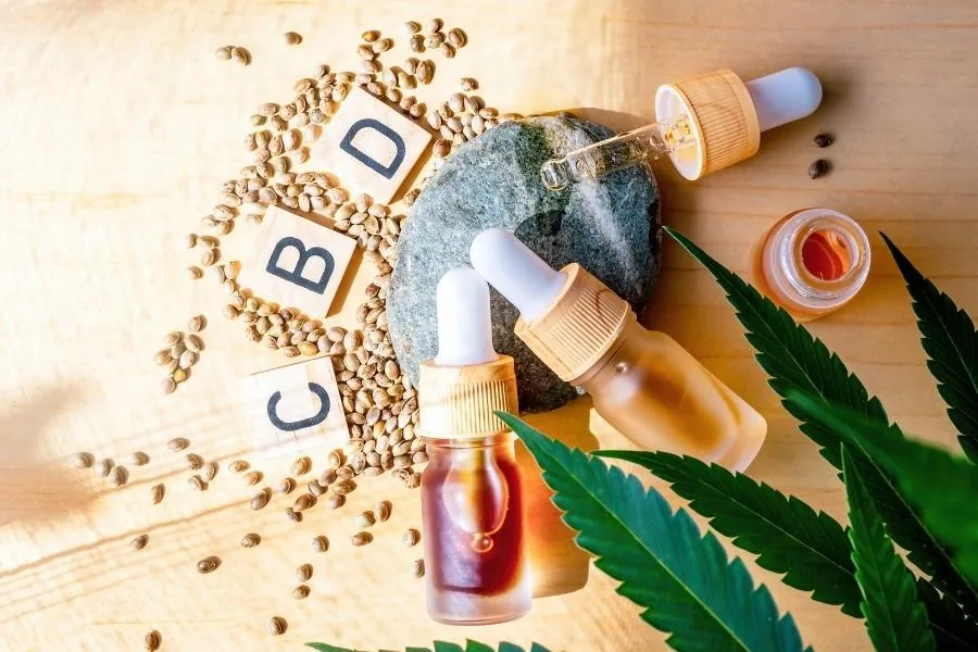 CBD oil droppers, hemp seeds and cannabis leaves on a wooden table